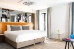 Chambre avec un lit blanc et une chaise bleue dans Renaissance Paris Vendome Hotel