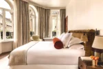 Chambre de luxe avec un grand lit blanc et des fenêtres Château des Fleurs Hôtel & Spa Paris