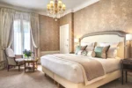 Chambre de luxe avec un grand lit et un lustre dans Hotel Westminster à Paris