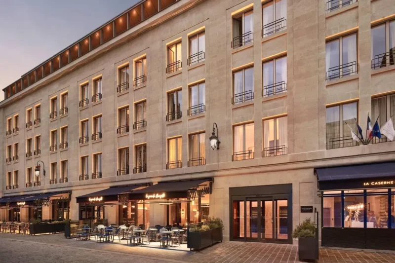 Grand bâtiment avec des tables et des chaises devant La Caserne Chanzy Hotel & Spa Autograph Collection à Reims