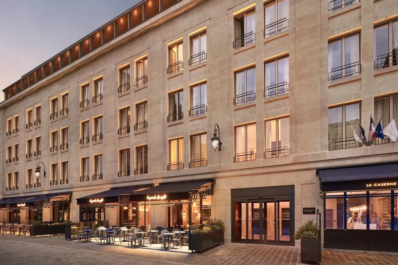 Grand bâtiment avec des tables et des chaises devant La Caserne Chanzy Hotel & Spa Autograph Collection à Reims