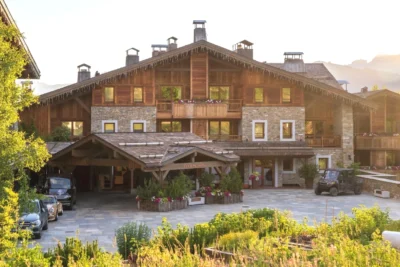 Grand bâtiment avec des voitures garées dans un parking Four Seasons Hotel Megeve
