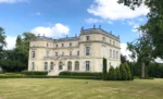 Grand bâtiment avec une cour herbeuse devant lui Château du Boulay Morin