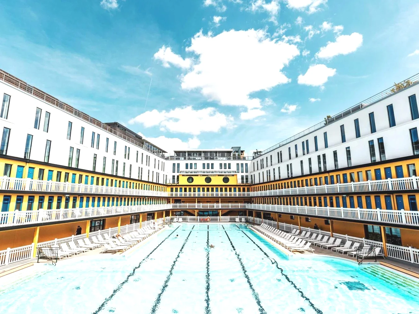 Grand bâtiment avec une piscine au milieu dans Molitor Hotel & Spa Paris MGallery Collection