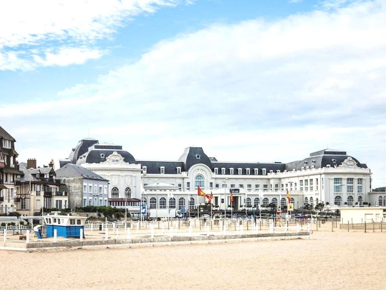 Grand bâtiment blanc sur la plage à côté du sable Cures Marines Hotel Thalasso & Spa Trouville MGallery Collection
