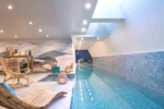 Piscine intérieure avec des chaises longues dans l'Hotel Parister Piscine & Spa à Paris