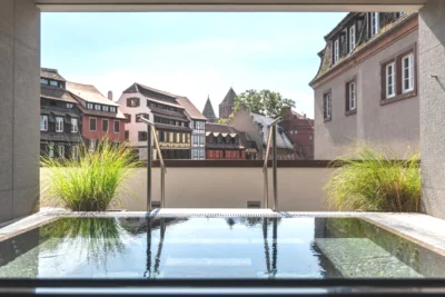 Piscine jacuzzi dans une cour avec des bâtiments dans Hotel & Spa REGENT PETITE FRANCE à Strasbourg
