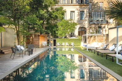 Une cour avec une piscine en face d'un bâtiment dans Le Palais Gallien Hôtel & Spa à Bordeaux